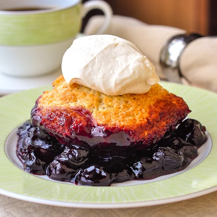Photo of a single serving of cherry cobbler ona green and white plate
